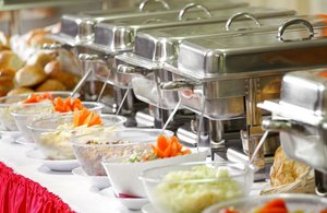 Warmhaltebehälter und Schüsseln am Buffet mit rotem Tischläufer